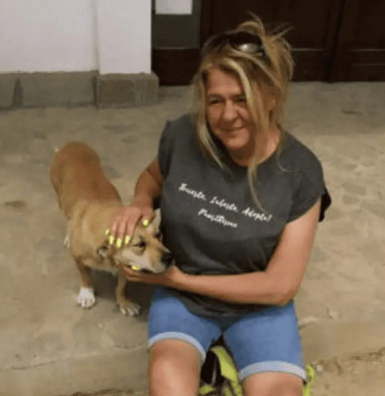 A photo of Paws2Rescue founder Alison sitting on a carpeted floor stroking a small dog